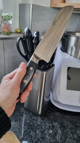 Ein Kunde hält ein Messer aus dem Kumai Kombipaket Nōburu in der Hand, der passende Messerblock steht im Hintergrund.