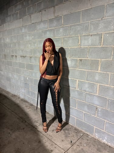 Reviewer standing against a wall wearing the black Vice Pant, showing its low-rise fit and side laces.