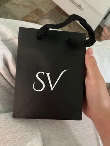 Cliente sosteniendo la bolsa de empaque negra de Saint Venik para la Pulsera Green Clover.