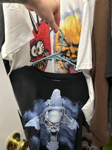 Customer holding a hanger showing three graphic shirts received in their 2025 Archive Mystery Box.