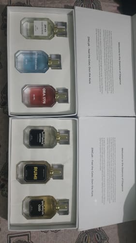 Customer displays two open OUD perfume bundles, showing the six different bottles inside their white boxes.
