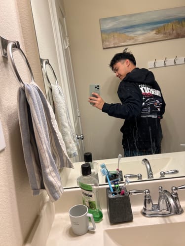 Reviewer taking a mirror selfie to show the back graphic of their black TOKYO RACING CLUB HOODIE.