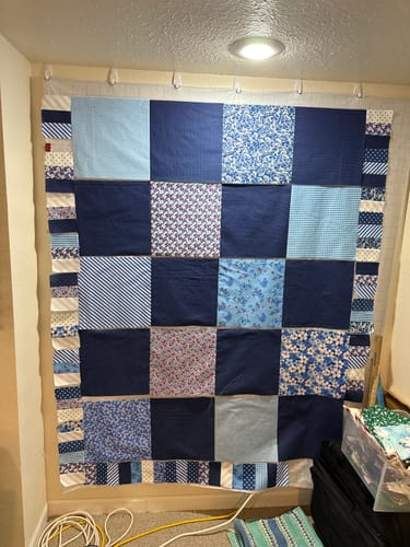 Customer's work-in-progress picnic blanket made from various blue and white patterned fabrics.