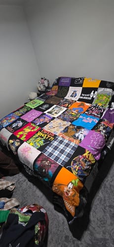 Customer's colorful Premium T Shirt Quilt made from various shirts, spread out on a bed.