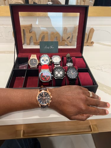 Customer's Lucky Fours® Voyager watch with a rose gold case on their wrist, in front of an open watch collection box.