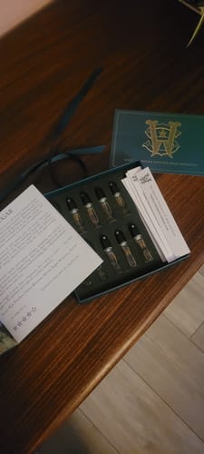 Customer's open Discovery Set with perfume samples and a guide book on a wooden table.
