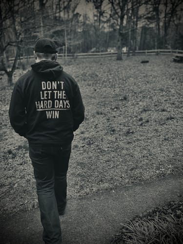 Reviewer seen from behind wearing the black Hard Days - Hoodie with 'Don't Let The Hard Days Win' on the back.