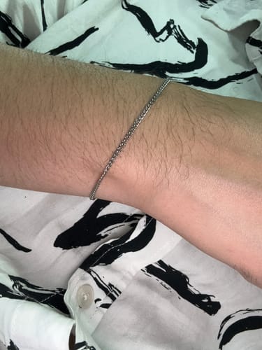 Primer plano de un cliente usando la delgada Pulsera Minimal Cuban 2mm en su muñeca.