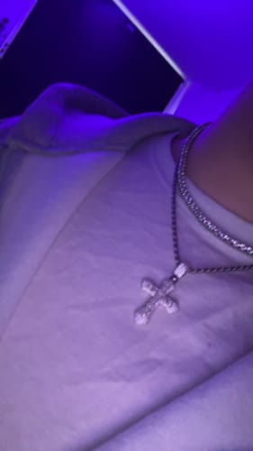Close-up of a customer wearing the sparkling FROSTY CROSS PENDANT on a chain.