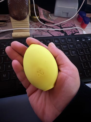Customer holding the yellow, lemon-shaped Lem Clitoral Massager in their hand.