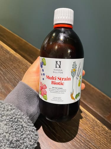 Reviewer holding the dark brown bottle of Multi Strain Biotic.