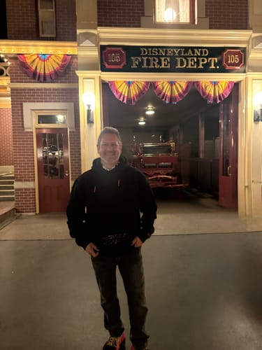 Reviewer wearing the black Disney "Midnight Mickeys" – Classic Hoodie at Disneyland at night.