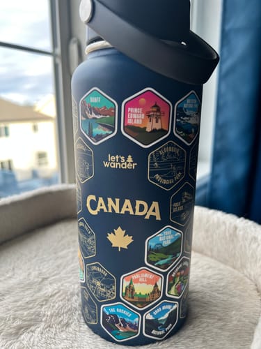 Customer's dark blue Canada Bottle featuring several colorful travel stickers for locations like Banff and Prince Edward Island.