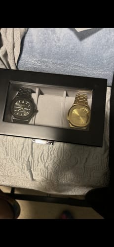 Customer's two Lucky Fours® Brone watches, one black and one gold, displayed in a sleek presentation box