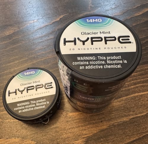 Customer's single can and a multi-pack roll of Glacier Mint nicotine pouches on a wooden surface.