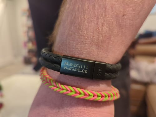 Close-up of a customer wearing the black Double Row Leather Bracelet, showing the personalized matte clasp.