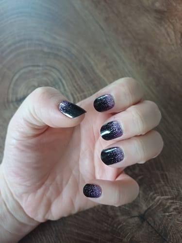 Rezensent zeigt eine Hand mit den 'Twilight Romance' UV Gel Nagelfolien mit einem schwarz-lila Glitzer-Ombré-Design.