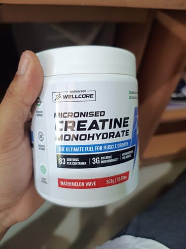 Customer holding a white tub of Wellcore Micronised Creatine Monohydrate in the Watermelon Wave flavor.