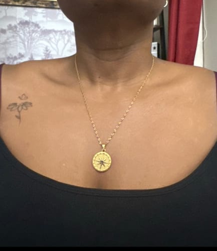 A reviewer wearing the gold Moonstar Necklace with a circular star-design pendant.
