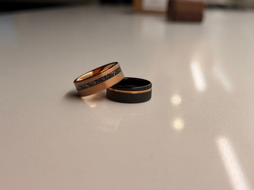 Customer's black Archer ring with rose gold inlay shown with another rose gold ring on a white countertop.