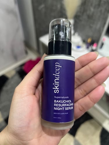 Reviewer holding the purple bottle of Bakuchiol Resurfacing Night Serum.