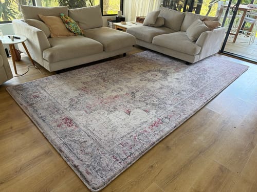 Customer's Aurora print Mellow Mat on a wooden floor in their living room, placed between two light-colored sofas.