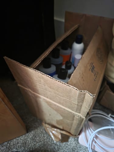 Partial view of a customer's cardboard box filled with various product bottles.