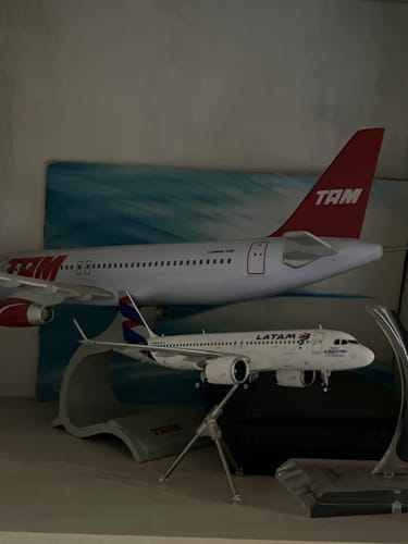 Reviewer's LATAM A320NEO model airplane displayed on its stand on a shelf with another model plane in the background.