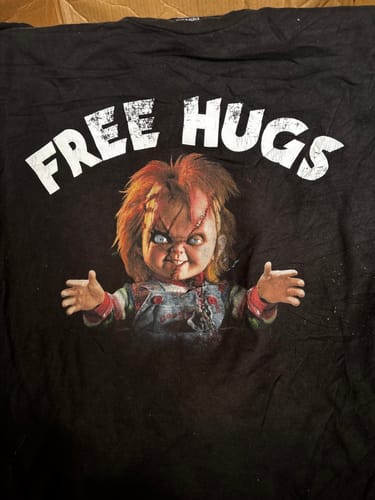 Customer shows a black t-shirt from their bale with a 'Free Hugs' Chucky graphic from the TV/Movies category.