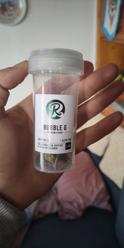 Customer holding a small, clear container of Bubble G THCA flowers in hand.