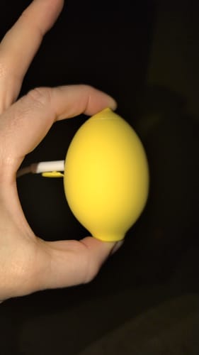 Reviewer holds the bright yellow, lemon-shaped Lem Clitoral Massager.