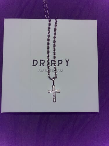 Customer's silver FAITH PENDANT, an iced-out cross on a rope chain, shown in front of its white brand box.