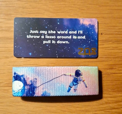 Reviewer displays the 'I'll Give You The Moon' bracelet and matching card with a colorful galaxy design.