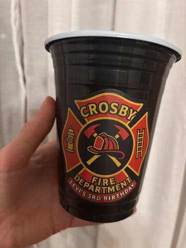Close-up of a customer's custom vinyl sticker with a red firefighter theme on a black cup.