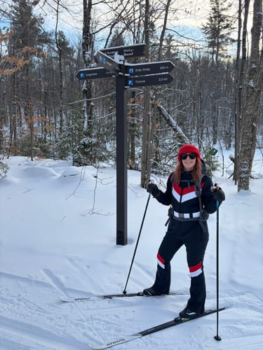 Reviewer wearing the color-block one-piece ski suit while skiing on a snowy trail.