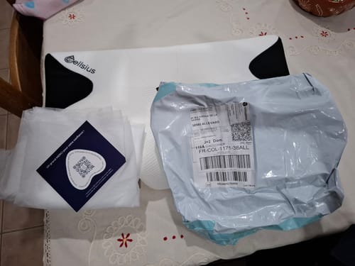 Photo d'un client montrant le coussin d'alignement cervical Cellsius déballé sur une table à côté de l'emballage d'expédition.