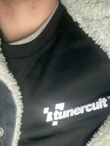 Close-up of a reviewer wearing the black 'tunercult' T-shirt from their TCG90 MYSTERY CASH BOX.