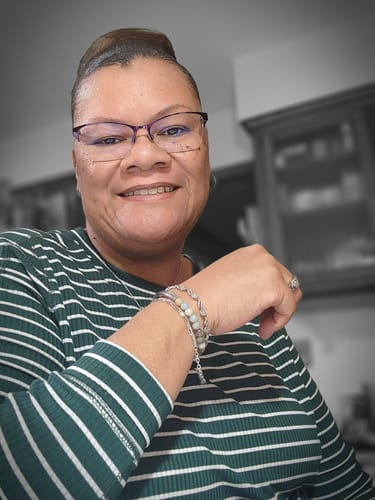 Reviewer smiling, showing the 'Find The Blessing In Everything' bracelet with light-colored beads on her wrist.