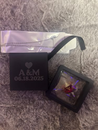 Customer's custom anniversary D20 dice in a display case next to its personalized black gift box.