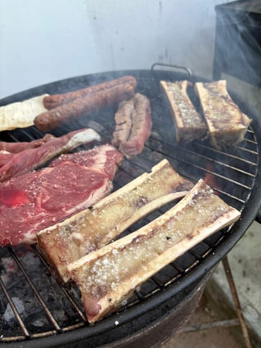Cliente asando un corte de Rib Eye Steak Prime en una parrilla de carbón.
