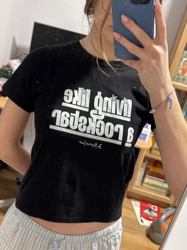 Reviewer taking a mirror selfie wearing the black graphic rockstar baby tee.