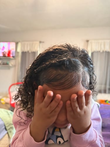 Customer's daughter showing her defined curly hair and styled baby hairs after using the curling cream and coiling jelly.