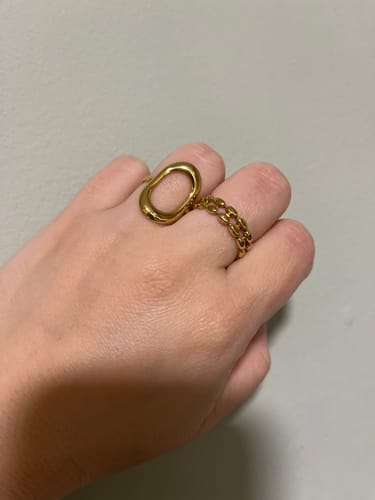 Customer's hand wearing two gold-colored rings, one with an abstract shape and one with a chain link design.
