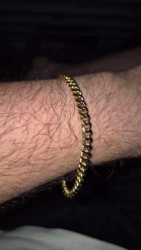 Primer plano de la Pulsera Miami Cuban dorada en la muñeca de un cliente.