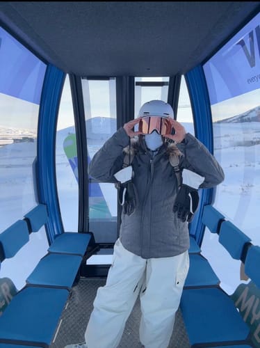Customer wearing the beige baggy snow pants while riding in a ski gondola.
