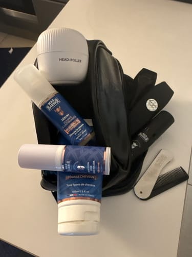 Client montrant sa trousse Max-Barber® noire ouverte, remplie de divers produits de toilettage.