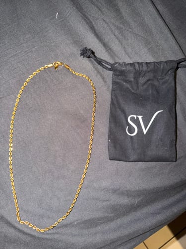 La Cadena Rope Oro de un cliente sobre una tela oscura, junto a su bolsa de guardado.
