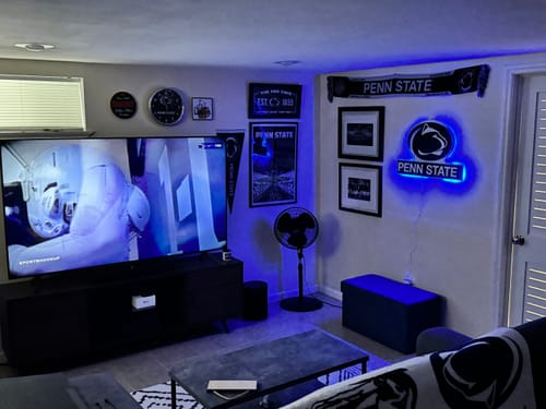 Customer's Penn State 3D Metal Wall Art with a bright blue LED glow, hanging in a media room.