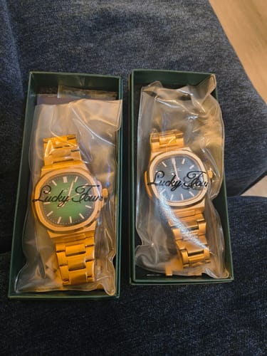 Customer's two gold Lucky Fours® Wraith watches in their green boxes. One has a green dial and the other has a dark dial.