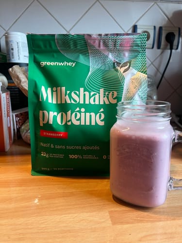 Photo d'un client : le sachet de Milkshake protéiné à la fraise à côté du shake rose préparé dans un verre.